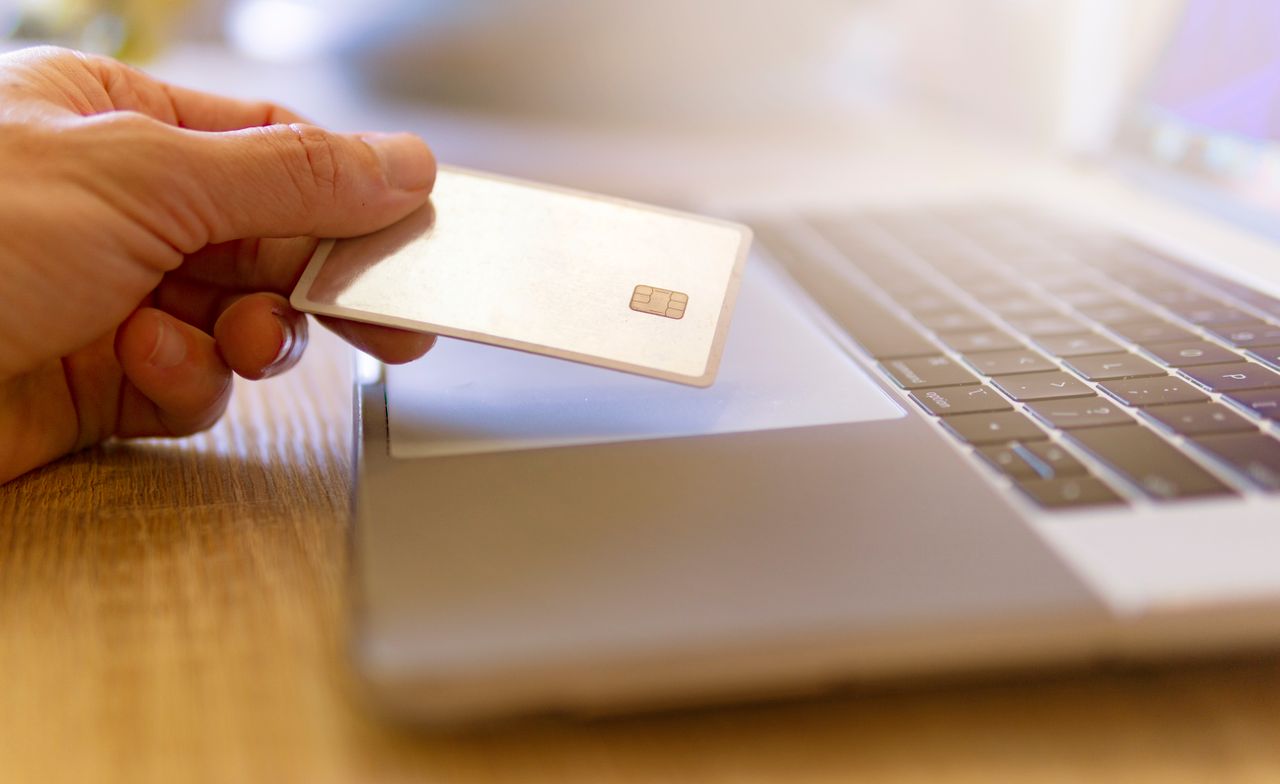 Contact A person holds a credit card near a laptop for online shopping.