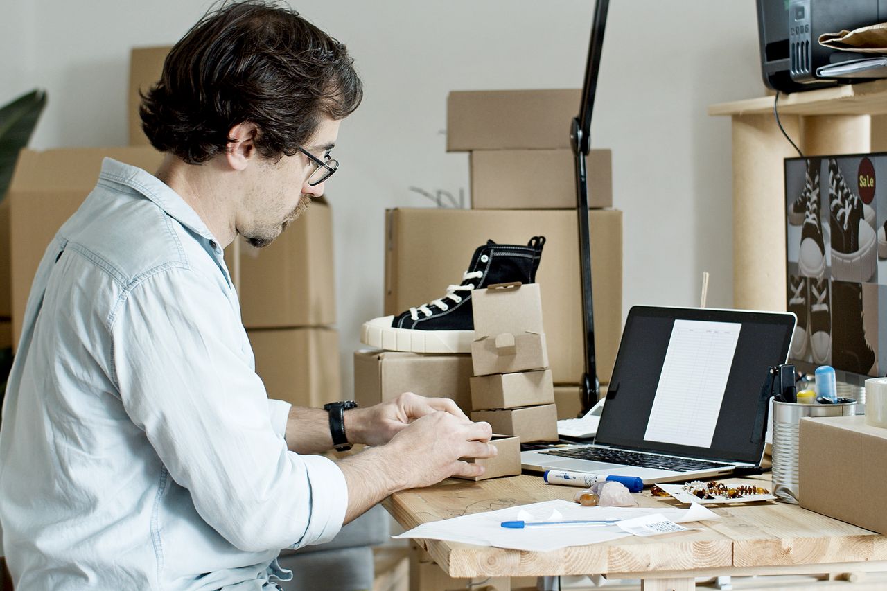About Businessman packing products and managing an online store from his desk with a laptop.